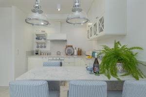 eine weiße Küche mit einem Tisch mit Stühlen und einer Pflanze in der Unterkunft Apartament Ambra Marina - Basen & SPA in Dziwnów