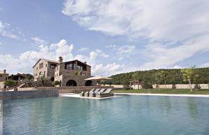 a mansion with a swimming pool in front of a house at La Vella Farga Hotel in Lladurs