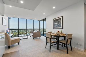 a dining room and living room with a table and chairs at Stunning cityview 1BR Apt, 1 min to train in Brisbane