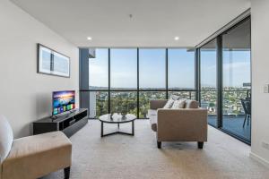 a living room with a couch and a tv and glass windows at Stunning cityview 1BR Apt, 1 min to train in Brisbane