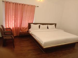 a bed sitting in a room with a window at Tulip in green meadows in Yercaud