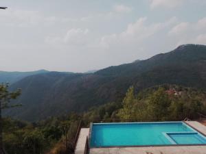 a swimming pool with mountains in the background at Tulip in green meadows in Yercaud