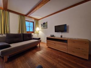 een woonkamer met een bank en een flatscreen-tv bij Kachelofenwohnung Pölzleitner in Annaberg im Lammertal
