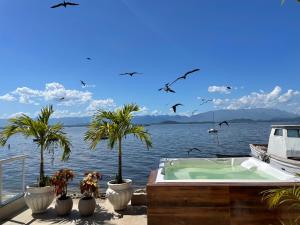 a boat in the water with palm trees and birds at Escondidinho Bar, hostel e casa de festas in Rio de Janeiro