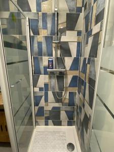 La salle de bains est pourvue d'une douche avec du carrelage bleu et blanc. dans l'établissement Studio cosy avec piscine, à Martigues