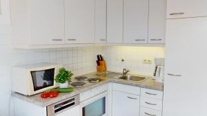 グレーミッツにあるGilde-Residenz App. 1の白いキャビネット、シンク、トマトが備わるキッチン