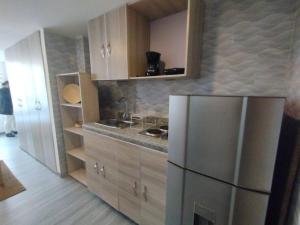 a kitchen with a stainless steel refrigerator and wooden cabinets at Centro Histórico: Estilo Ejecutivo in Bogotá