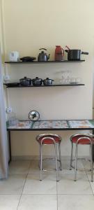 une cuisine avec deux tabourets et un comptoir avec des casseroles et des poêles dans l'établissement Kitnet Marília, à Marília