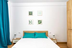 a bedroom with a white bed with blue pillows at Apartament Central in Craiova