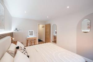 a white bedroom with a bed and a desk at Stylish and modern city centre apartment with easy parking in Worcester