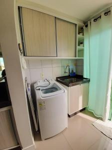 eine kleine Küche mit einer Waschmaschine und einem Waschbecken in der Unterkunft Cobertura Ap praia de Bombas in Bombinhas