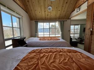 2 Betten in einem Zimmer mit 2 Fenstern in der Unterkunft Hakuba Snow Fox in Hakuba