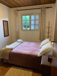 a bedroom with a large bed and a window at Cantinho nascer do sol in Campos do Jordão