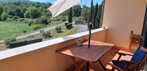 einen Balkon mit einem Holztisch und einem Sonnenschirm in der Unterkunft 3-Bed Duplex Apartment in Vepri close to Siena in Bucine