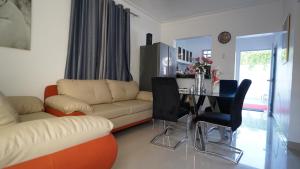 ein Wohnzimmer mit einem Sofa und einem Tisch mit Stühlen in der Unterkunft Villa Sol Taino, Hotel en Boca chica, 5 minutos del Aeropuerto Internacional las Américas in La Golondrina