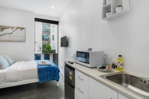 una cocina con fregadero y una cama en una habitación en Urban Thrive Studio is in a great location en Auckland