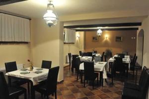 un restaurant avec des tables blanches, des chaises noires et un chercheur de table dans l'établissement Regent Garden, à Băile Felix