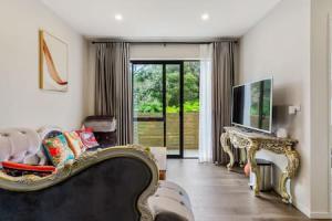 a living room with a couch and a television at Grand Retreat with spa pool and parking in Auckland