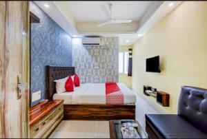 Hotel Deep Chinarpark,Near kolkata airport في Salua: غرفة نوم بسرير ومخدات حمراء واريكة