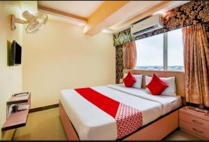 Hotel Deep Chinarpark,Near kolkata airport في Salua: غرفة نوم بسرير ومخدات حمراء ونافذة