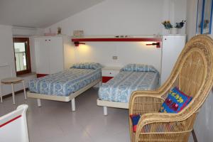 a bedroom with two beds and a wicker chair at Appartamenti Rosanna in Grado