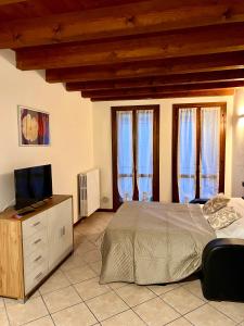 ein Schlafzimmer mit einem Bett und einem TV auf einer Kommode in der Unterkunft Alloggi Mincio in Goito