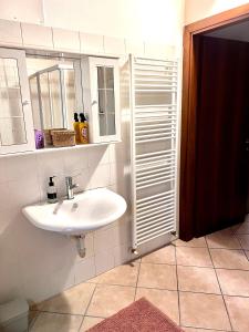 W łazience znajduje się biała umywalka i lustro. w obiekcie Alloggi Mincio w mieście Goito