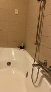 a white bath tub with a shower in a bathroom at Kennedy Apartment in Quattromiglia