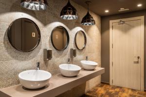 three sinks in a bathroom with three mirrors at Arya Stadium Hotel in Barcelona