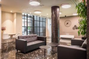 a lobby with a couch and tables and a clock at Arya Stadium Hotel in Barcelona