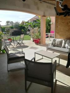 un patio con sillas, una mesa y un sofá en Chambre privée entrée indépendante piscine familiale chauffée, 4 min du Puy du Fou, en Les Épesses