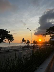 a sunset on a beach with palm trees and the ocean at Hotel Nacional in Rio de Janeiro