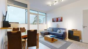 a living room with a blue couch and a table at DünenResort in Binz, strandnahe und moderne FeWos mit Balkon, teilweise mit Meerblick, in Binz