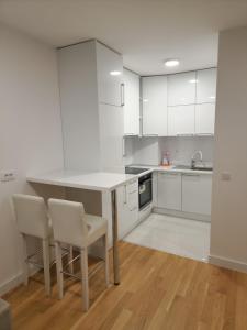 - une cuisine avec des placards blancs, une table et des chaises dans l'établissement Apartment 4th. Floor II, à Banja Luka