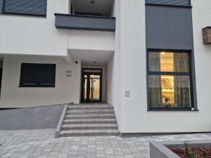 - un bâtiment blanc avec des escaliers menant à une porte dans l'établissement Apartment 4th. Floor II, à Banja Luka