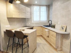- une cuisine avec un comptoir et deux tabourets dans l'établissement Le Cocon Design - Gare / Centre ville de Caen, à Caen