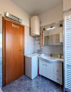 uma casa de banho com um lavatório e uma máquina de lavar roupa em Apartmani Skejic em Split