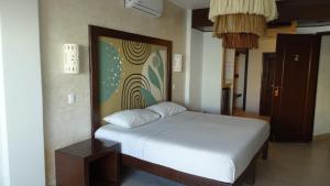 a bedroom with a white bed and a painting on the wall at Hotel Boutique Kinich in Isla Mujeres