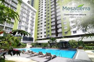 a swimming pool with chairs in front of some buildings at Cozy Studio Condo at Mesatierra Garden Residences in Davao City