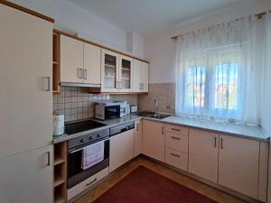 uma cozinha com armários brancos, um lavatório e um micro-ondas em Apartmani Skejic em Split