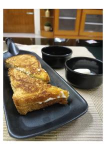 a black plate with a piece of toast on a table at ATULYAM HARSHADA STAYS LUCKNOW in Goshainganj