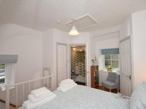 a white bedroom with a bed and a bathroom at 1 bed in Pwllheli 60173 in Pwllheli