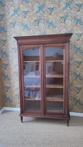 a wooden cabinet with glass doors in a room at Maison Charmeilles - La suite Saint Emilion in Fronsac