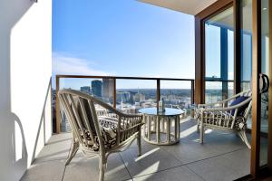 a balcony with two chairs and a table on a building at Chic Zenith Retreat -Vista, Skylight, Parking in Sydney