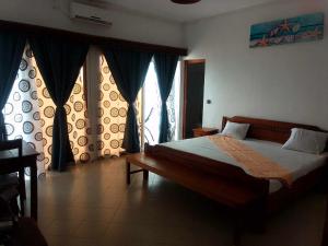 a bedroom with a bed and windows with curtains at RAOOF HOTEL in Mahajanga