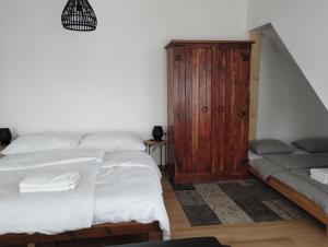 a bedroom with two beds and a wooden cabinet at Attic apartment Cathouse in Bratislava