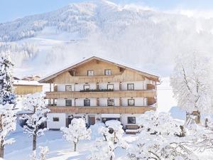 un grand bâtiment dans la neige avec des arbres enneigés dans l'établissement Hirzingerhof, à Westendorf