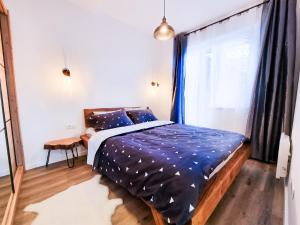 a bedroom with a bed with blue comforter and a window at Vucko Slopes Apartment Bjelasnica in Bjelašnica