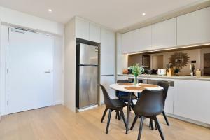 La cuisine est équipée d'une table, de chaises et d'un réfrigérateur. dans l'établissement Chic Zenith Retreat -Vista, Skylight, Parking, à Sydney