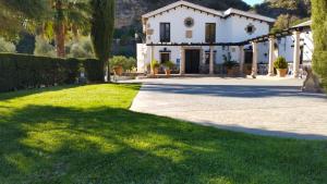 une grande maison blanche avec une cour en herbe dans l'établissement Hotel La Hoya del Tajo, à Ronda